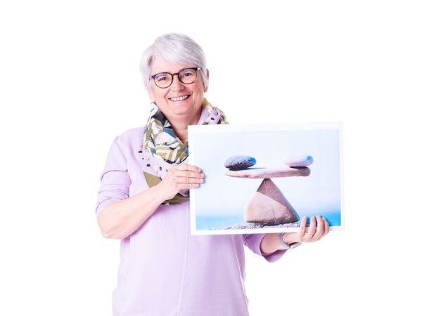 Susanen Hödl hält ein Bild mit einer Waage und lächelt