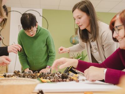 Eine Assistenz unterstützt Assistenznehmer*innen bei kreativer Arbeit