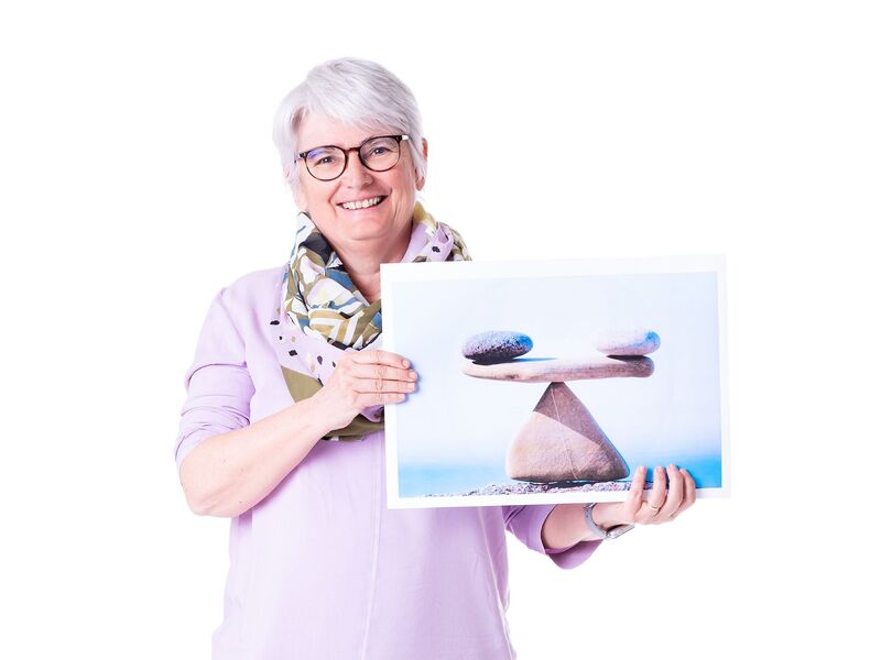 Susanen Hödl hält ein Bild mit einer Waage und lächelt