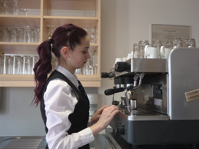 Eine junge Kellnerin beim Kaffee machen