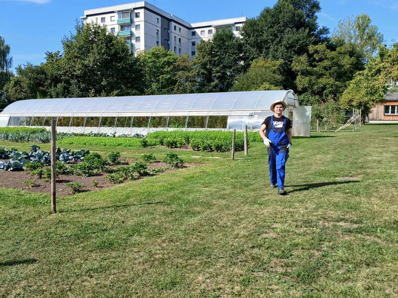 Ein junger Assistenznehmer geht durch den Stadtgarten